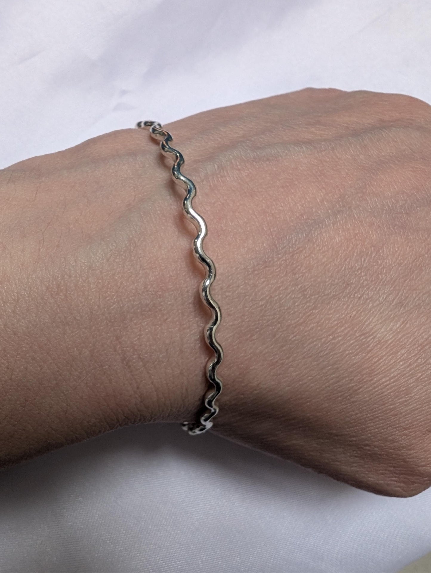 Wiggly sterling silver bangle being worn