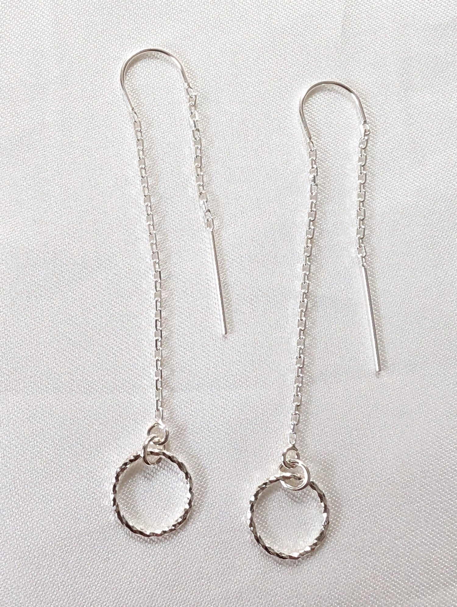 A pair of sterling silver threader earrings with sparkly circle charms and U bar to ensure threader dangles both sides of the ear.