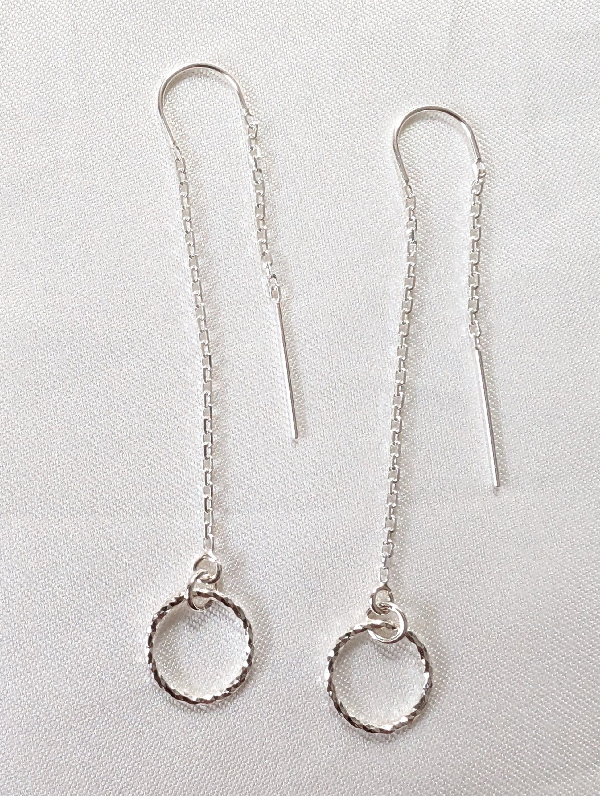 A pair of sterling silver threader earrings with sparkly circle charms and U bar to ensure threader dangles both sides of the ear.