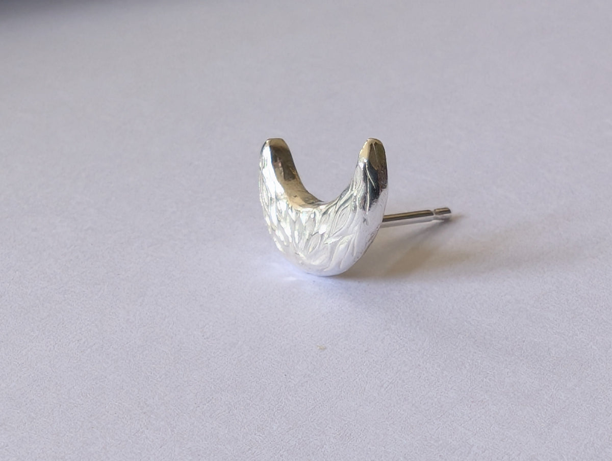 Silver earring on a light gray background