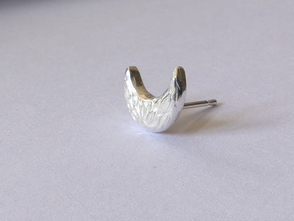Silver earring on a light gray background
