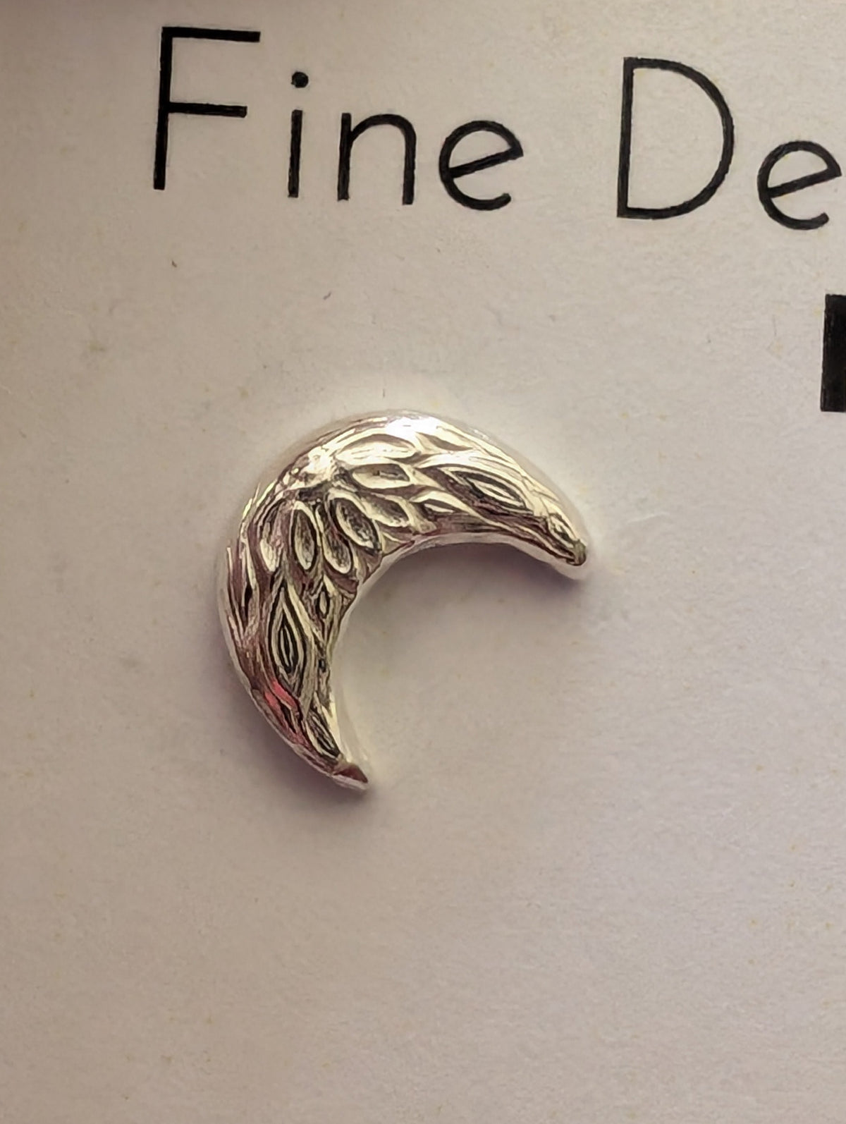close up of botanical-type pattern on moon earring